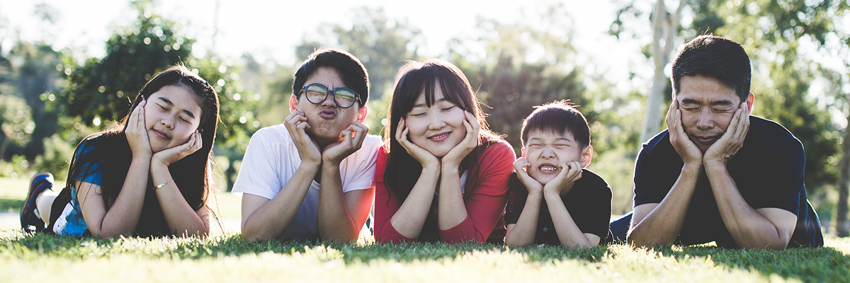 Family sitting in the grass and making funny faces